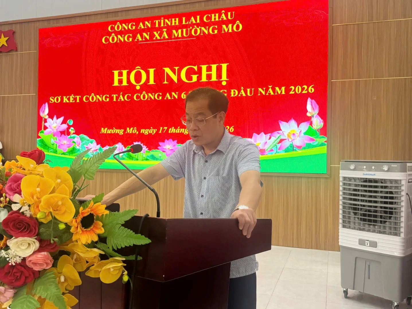 A person standing at a podium with a podium and flowers

Description automatically generated
